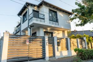 a white house with a wooden fence in front of it at Cris Apartments in Târgu-Mureş