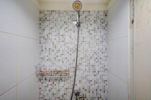 um chuveiro na casa de banho com uma parede de azulejos em OYO Life 92874 Apartement Grand Sentraland Karawang By Red Dragon em Karawang