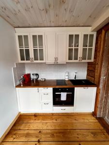 eine Küche mit weißen Schränken und einer schwarzen Mikrowelle in der Unterkunft Juveliera apartamenti in Kuldīga