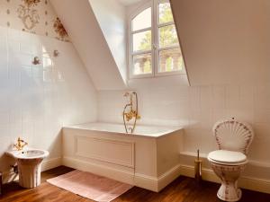 ein Bad mit einer Badewanne, einem WC und einem Fenster in der Unterkunft Château du Prieuré Évecquemont Les Mureaux in Évecquemont