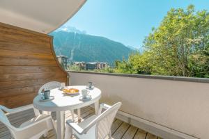 una mesa y sillas en un balcón con vistas en Résidence Le Cristal - Mont Blanc 6 - Happy Rentals, en Chamonix-Mont-Blanc
