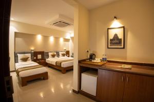 Metro Plaza Hotel في منغالور: غرفة فندقية بسريرين ومطبخ