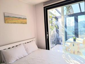 Un dormitorio con una cama y una ventana grande. en Siyoung's House, en Jeju