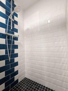 bagno con doccia e piastrelle bianche e blu di Gîte Le P'tit Chez Nous a La Rochefoucauld