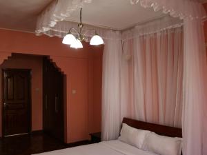 a bedroom with a bed with white curtains and a chandelier at KenGen Furnished and Serviced Apartments in Nairobi