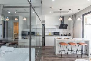 a kitchen with white cabinets and a counter with stools at Vinhomes Dcapital Tran Duy Hung Official in Hanoi