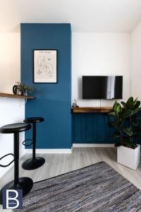 una sala de estar con una pared azul y dos taburetes en Le Bataillon - Confort en Compiègne