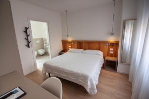 a bedroom with a white bed and a bathroom at Hotel Oliva in Aviano