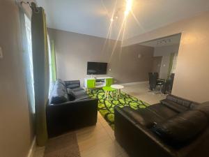 a living room with a leather couch and a tv at Juke's Serene Westlands Villa in Nairobi