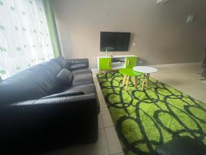 uma sala de estar com um sofá preto e um tapete verde em Juke's Serene Westlands Villa em Nairobi