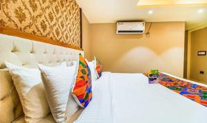 a bedroom with a large white bed with colorful pillows at FabHotel SVR in Patna