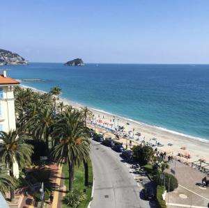 - une vue sur la plage bordée de palmiers et l'océan dans l'établissement Appartamento in centro a 30m dal mare, à Spotorno