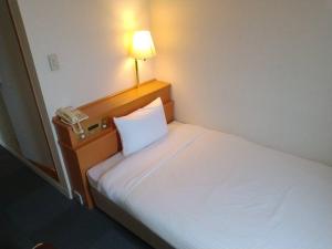 1 dormitorio con 1 cama con lámpara y teléfono en Kitami Daiichi Hotel, en Kitami