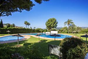 una piscina con sombrillas en un parque en La Blanqueta- Alcasar en Moraira