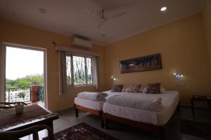a bedroom with two beds and a large window at lalita homestay countryside in Khajurāho