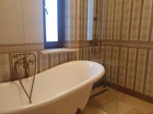 La salle de bains est pourvue d'une baignoire et d'une fenêtre. dans l'établissement Poiana Golf Chalet, à Buşteni