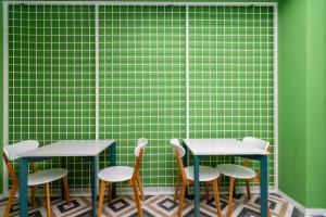 two tables and chairs in front of a green wall at Sololaki Inn in Tbilisi City
