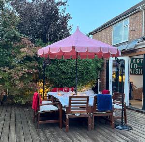 a table with a pink umbrella on a deck at Modern, Gr Floor 1 bed, bathroom, garden & private entry. in Cambridge