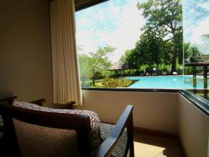 a room with a large window with a view of a swimming pool at River Tree Resort in Chiang Khan