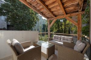 a patio with wicker furniture and a wooden pergola at Apartments Old Town Gloria in Zagreb