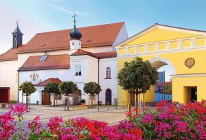 a large yellow and white building with a church at Römer Apartment und Zimmer in Türkheim