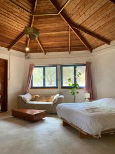 a bedroom with two beds and a couch and windows at the Meshushe in Kadita