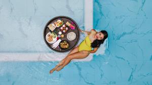a woman in a swimming pool with a plate of food at Tour De Phuket Hotel - SHA Plus in Thalang