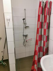 a shower with a red and white curtain next to a sink at Zimmervermietung LanNik in Hildesheim