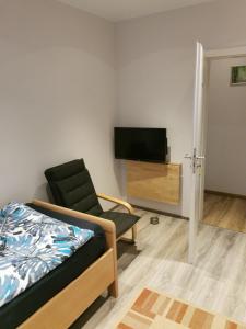 um quarto com uma cama, uma cadeira e uma televisão em Zimmervermietung LanNik em Hildesheim