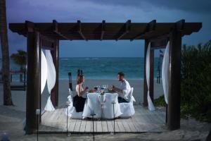 people sitting at a table in front of a beach at Punta Cana Princess Adults Only - All Inclusive in Punta Cana