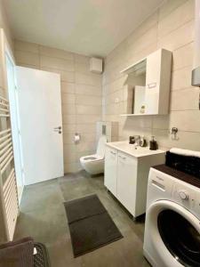 a bathroom with a toilet sink and a washing machine at New modern APT near Old town - private parking in Zadar