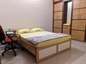 a bedroom with a bed and a chair in it at Athreyas@60/A in Mysore