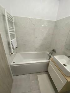 Baño blanco con bañera y lavamanos en Apartament tip studio, en Roşu