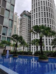 a large swimming pool with palm trees in front of tall buildings at SOHO Suites KLCC in Kuala Lumpur