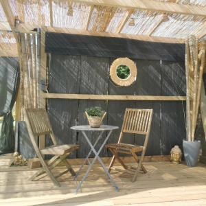 2 Stühle und ein Tisch auf der Terrasse in der Unterkunft Logement cosy avec piscine et jacuzzi privatifs 4 étoiles in Saint-Dolay