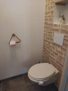 a bathroom with a white toilet and a brick wall at Petite maison au calme in Poupry