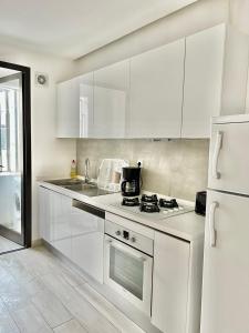uma cozinha branca com armários brancos e um frigorífico em "Luxe Residence" Marsa avec Parking em Tunes