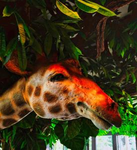 a giraffe head hanging from a tree at Amicitia - Hôtel & Restaurant in LʼIsle-Adam