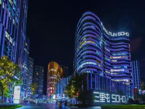 a tall building with lights on it at night at Happy Dragon City Center Alley Hotel -In the city center with big window&heater, ticket service&Free Coffee&Food recommendation,Near Tian Anmen Forbiddencity,Easy to get traditional Walking area&Shichahai in Beijing