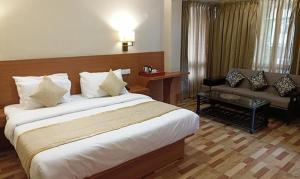 um quarto de hotel com uma cama grande e um sofá em FabHotel Prime Denzong Shiron em Gangtok