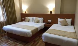 um quarto de hotel com duas camas e duas lâmpadas em FabHotel Prime Denzong Shiron em Gangtok
