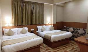 um quarto de hotel com duas camas e um sofá em FabHotel Prime Denzong Shiron em Gangtok