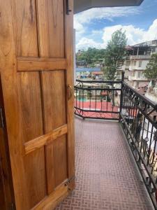 eine offene Holztür auf einem Balkon mit Gehweg in der Unterkunft Stay Inn Belle Vue House in Shillong