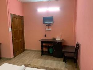 Zimmer mit einem Schreibtisch und einem TV an der Wand in der Unterkunft Stay Inn Belle Vue House in Shillong