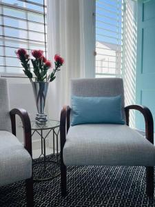 una habitación con una silla y una mesa con un jarrón con flores en Cottage, Nine on Windsor, Kalk Bay, Cape Town, en Kalk Bay