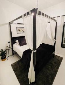 1 dormitorio con 1 cama en blanco y negro con dosel en Cottage, Nine on Windsor, Kalk Bay, Cape Town, en Kalk Bay