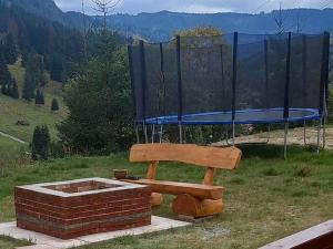 a wooden bench sitting in front of a trampoline at Cabana Corbilor The Raven's Hut in Vatra Dornei