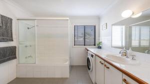 a white bathroom with a shower tub and a sink at Copacabana House - Absolute Waterfront, Private Jetty in Yamba +15 photos