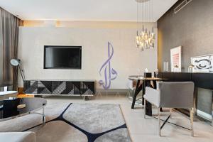 a living room with a tv and a dining room at Walaa Homes Stylish 1BR at DAMAC Esclusiva tower Riyadh-M07 in Riyadh