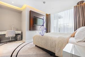 Walaa Homes Stylish 1BR at DAMAC Esclusiva tower Riyadh-M07 في الرياض: غرفة نوم بسرير كبير وتلفزيون